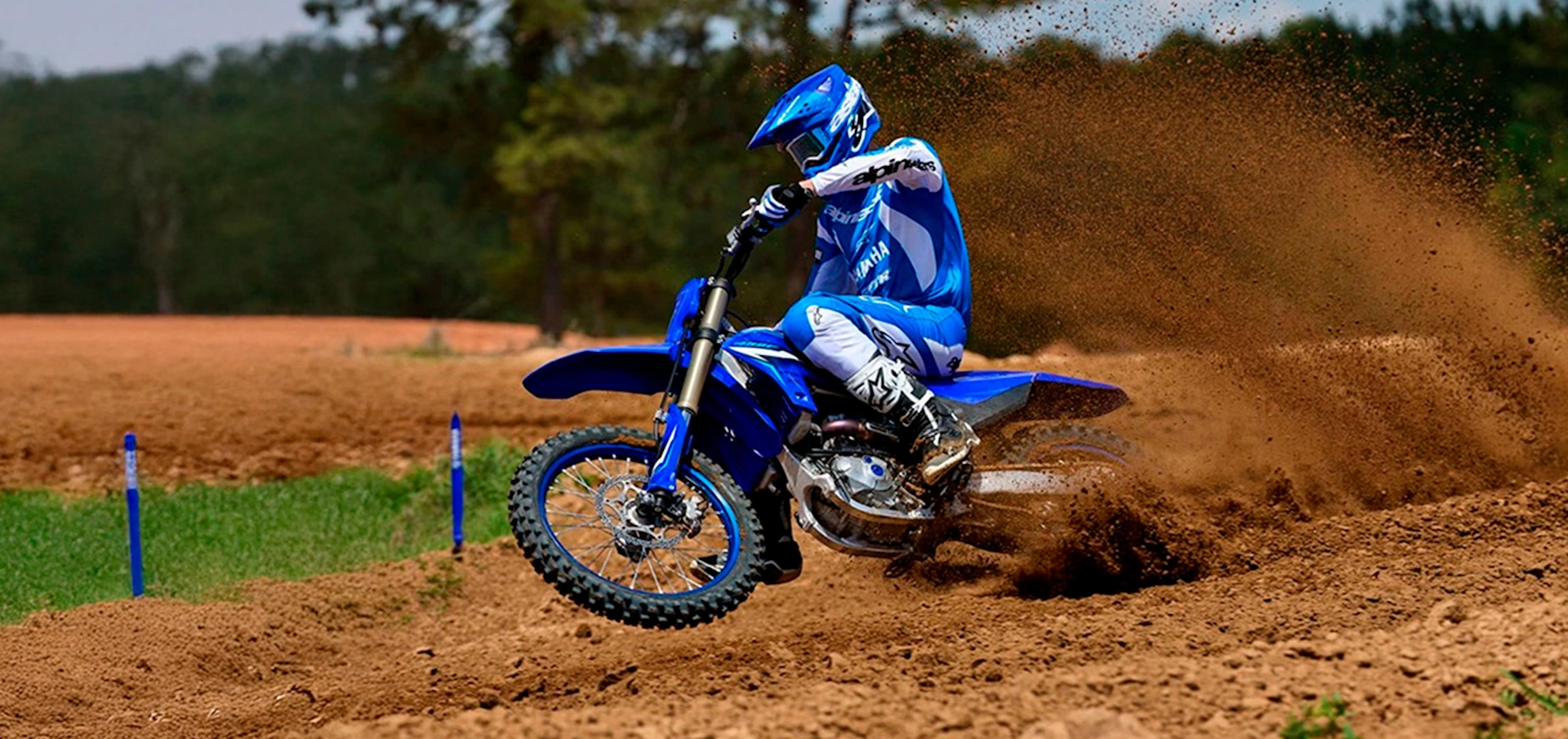 A man going full speed on a racing blue byke with blue uniform